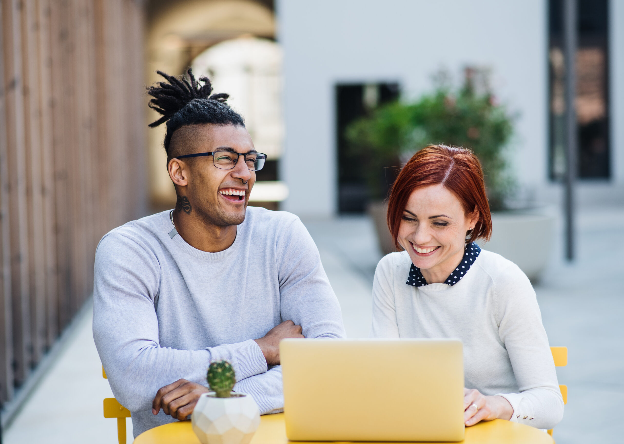 Young businesspeople with laptop in courtyard, start-up concept.